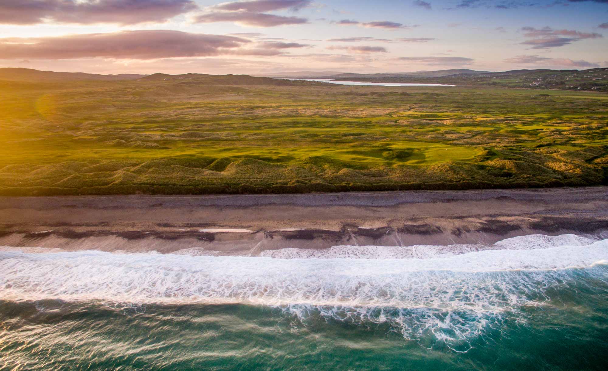 An aerial photo of the Ballyliffin Golf Club Glashedy Golf Course and the crashing waves of the Atlantic.