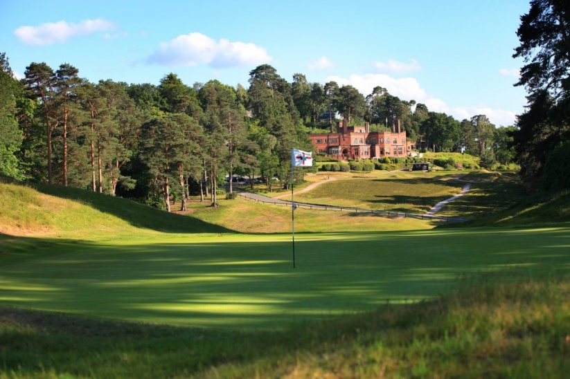 The 1st green with the iconic brick clubhouse at St Georges Hill Golf Club.